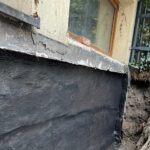 Izolacja fundamentów w starym domu – powłoka bitumiczna na odkopanej ścianie