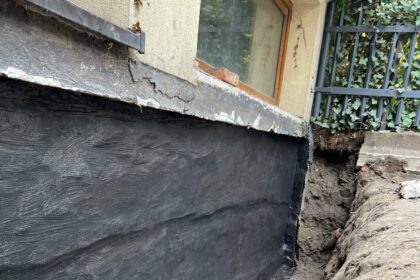 Izolacja fundamentów w starym domu – powłoka bitumiczna na odkopanej ścianie