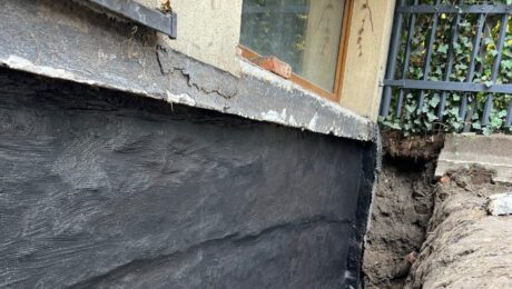Izolacja fundamentów w starym domu – powłoka bitumiczna na odkopanej ścianie