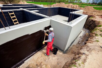 Aplikacja materiałów uszczelniających na ściany budynku w celu hydroizolacji.