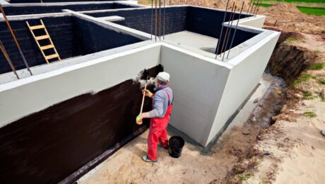 Aplikacja materiałów uszczelniających na ściany budynku w celu hydroizolacji.