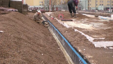 Pracownicy układają warstwę hydroizolacyjną na placu budowy.