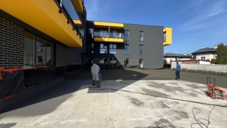 Robotnicy pracują nad izolacjami tarasów w nowoczesnym budynku.