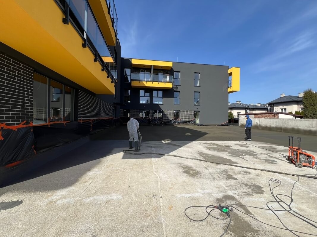 Robotnicy pracują nad izolacjami tarasów w nowoczesnym budynku.