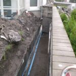 Prace związane z uszczelnianiem betonu przy ścianie budynku.