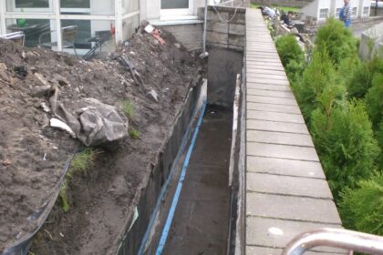 Prace związane z uszczelnianiem betonu przy ścianie budynku.