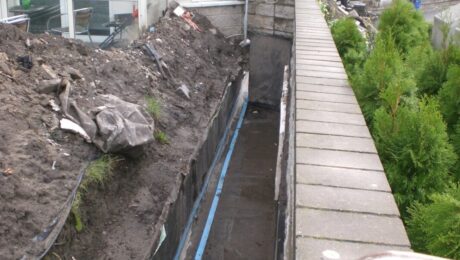 Prace związane z uszczelnianiem betonu przy ścianie budynku.