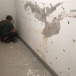 Mężczyzna pracuje nad ścianą, przygotowując ją do procesu iniekcji ciśnieniowej.