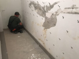 skuteczna-iniekcja-cisnieniowa.jpg Mężczyzna pracuje nad ścianą, przygotowując ją do procesu iniekcji ciśnieniowej.