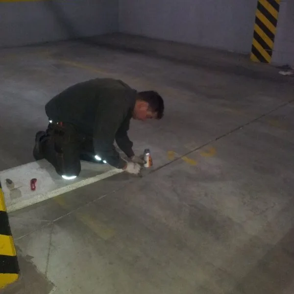 Pracownik uszczelnia szczelinę w posadzce garażu podziemnego