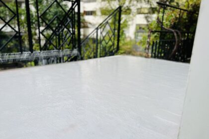 Izolacja balkonu – świeżo nałożona biała warstwa hydroizolacji na powierzchni tarasu.