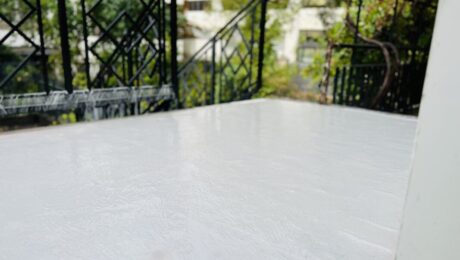 Izolacja balkonu – świeżo nałożona biała warstwa hydroizolacji na powierzchni tarasu.