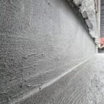 Izolacje przeciwwilgociowe na ścianie fundamentowej wykonane warstwą szarej masy hydroizolacyjnej.