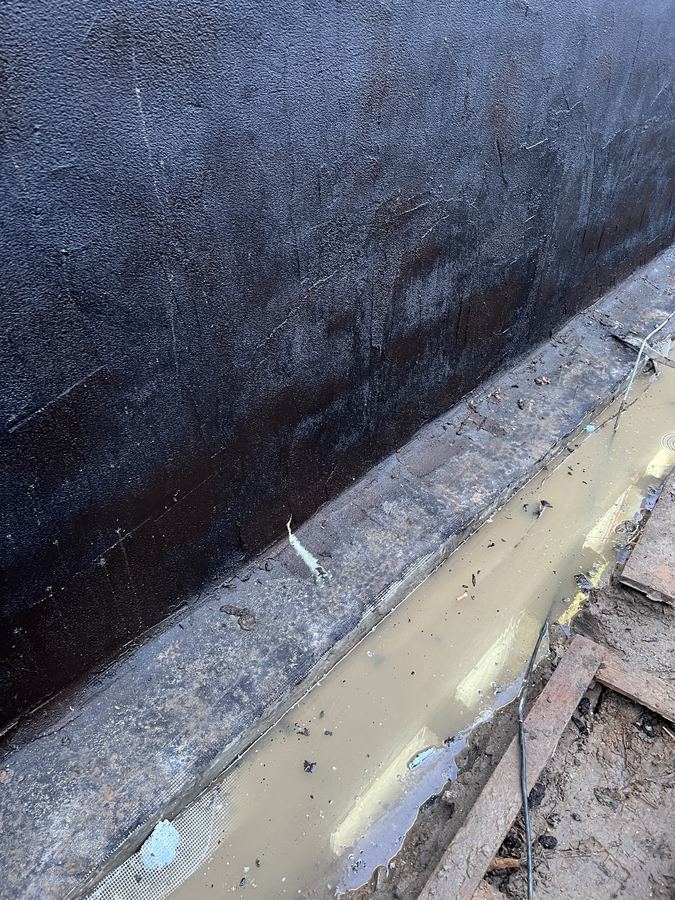 Zbliżenie powłoki bitumicznej na murze fundamentowym starego budynku