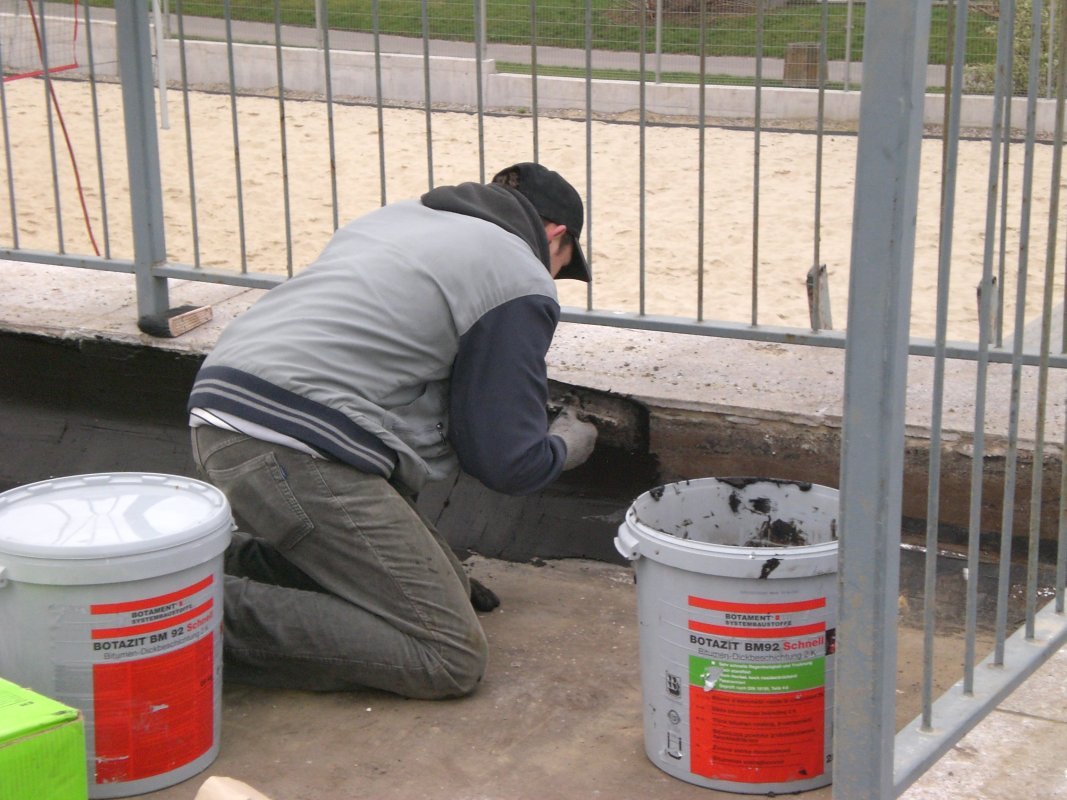 Nakładanie bitumicznej masy hydroizolacyjnej na ścianę fundamentową