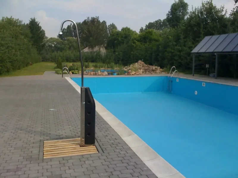 Basen ogrodowy z niebieską folią i prysznicem na nawierzchni z kostki