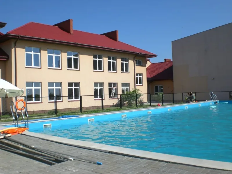 Napełniony basen zewnętrzny przy budynku z czerwonym dachem