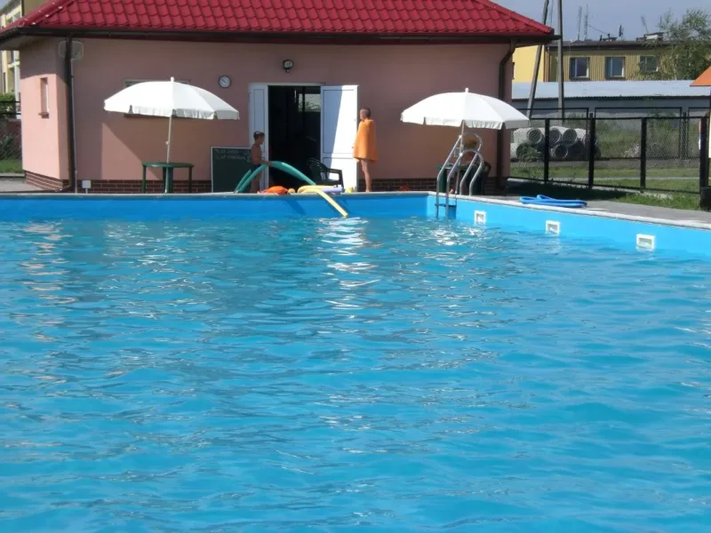 Basen zewnętrzny z parasolami przy budynku zaplecza