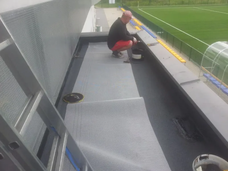Pracownik przy obróbce membrany na dachu trybuny stadionu