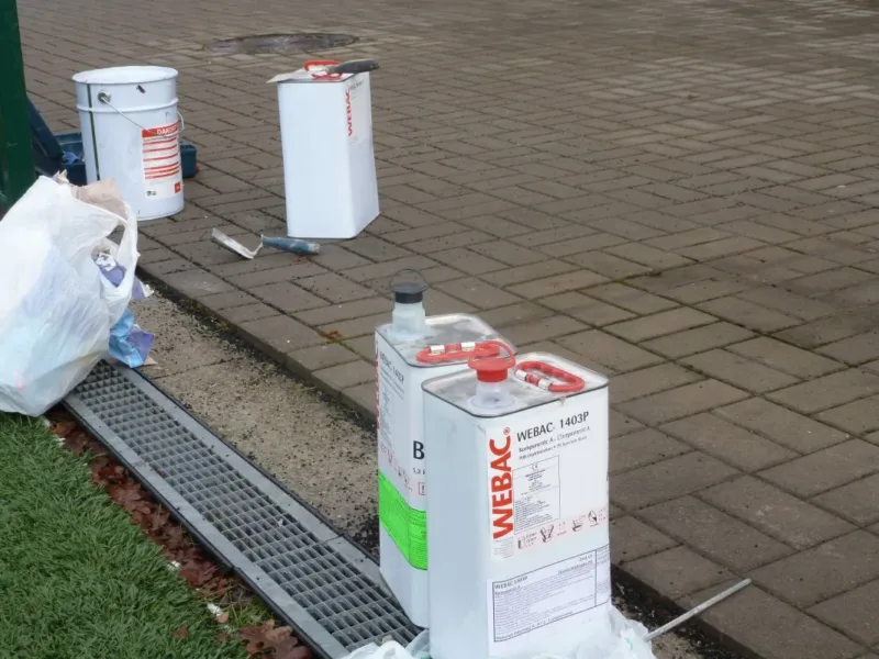 Pojemniki z materiałami uszczelniającymi na nawierzchni z kostki przy odwodnieniu