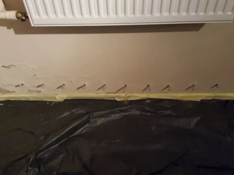Pakery w dolnej części ściany pod grzejnikiem, podłoga zabezpieczona folią