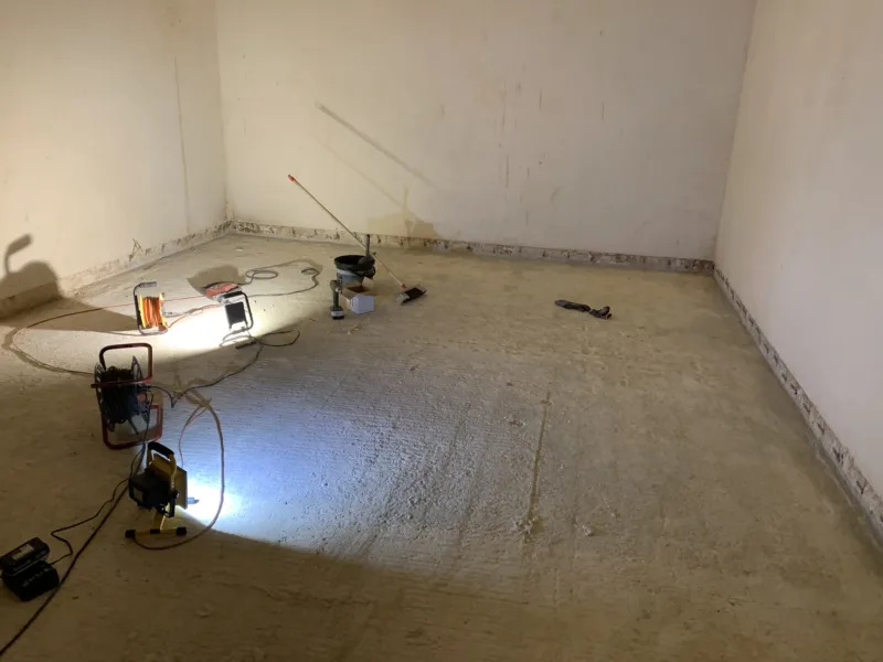 Puste pomieszczenie z pakerami wzdłuż styku ścian i posadzki, oświetlone lampami roboczymi
