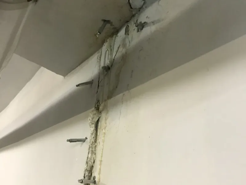 Pęknięcie w narożniku ściany i stropu z pakerami i spływami żywicy