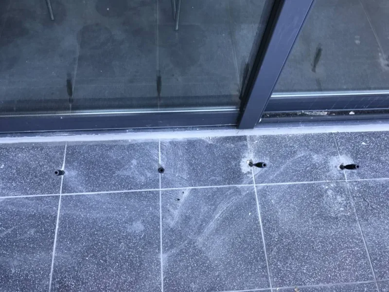 Pakery w posadzce z płytek przy przeszklonej ścianie - uszczelnienie styku z fasadą