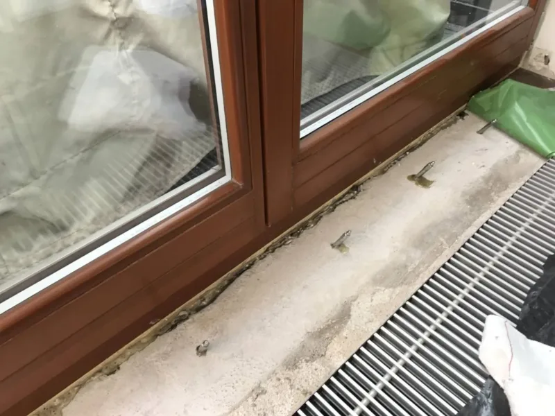 Pakery w posadzce przy progu drzwi balkonowych, obok kratka grzejnika kanałowego