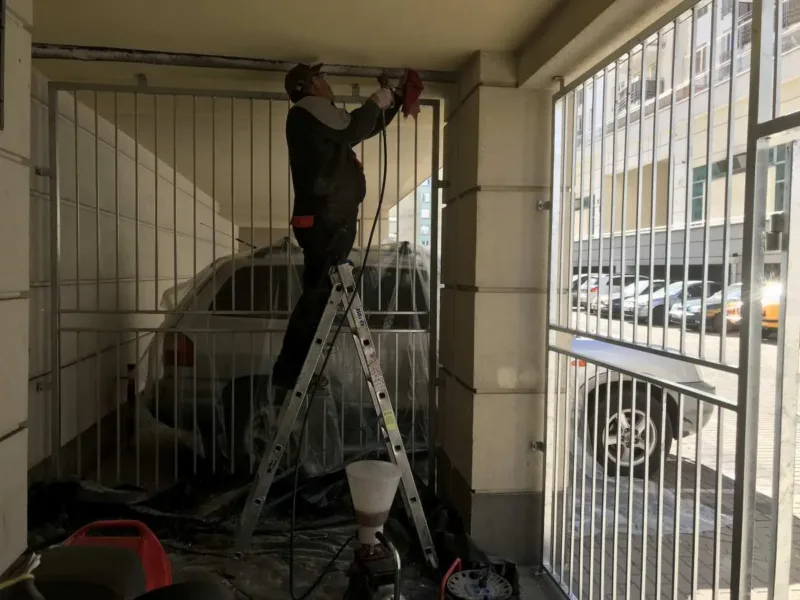Pracownik na drabinie przy iniekcji górnej części ściany w boksie garażowym
