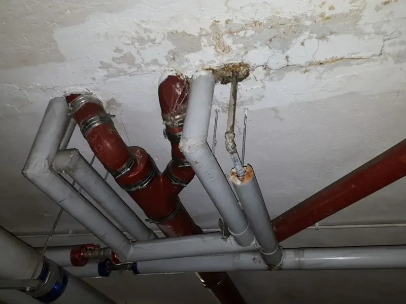 Zawilgocony strop przy przejściu rur instalacyjnych w pomieszczeniu technicznym