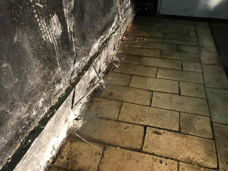 Styk ściany i posadzki z kostki z rzędem pakerów, ściana pokryta czarną powłoką