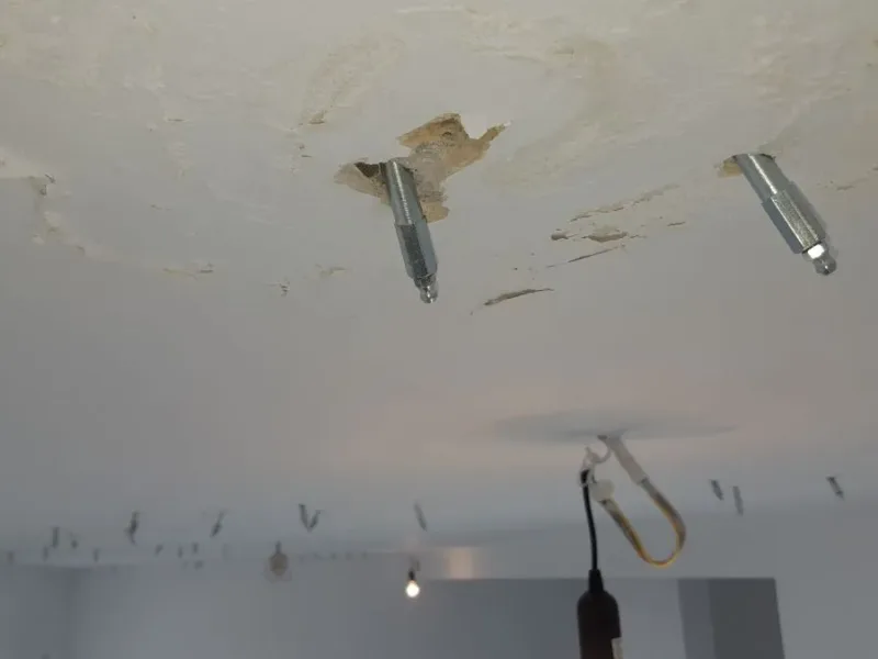 Sufit z pakerami i zaciekami wokół lampy