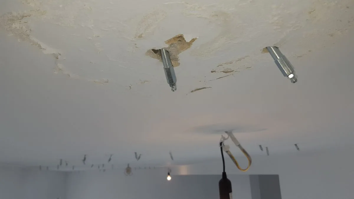 Sufit z pakerami i zaciekami wokół lampy