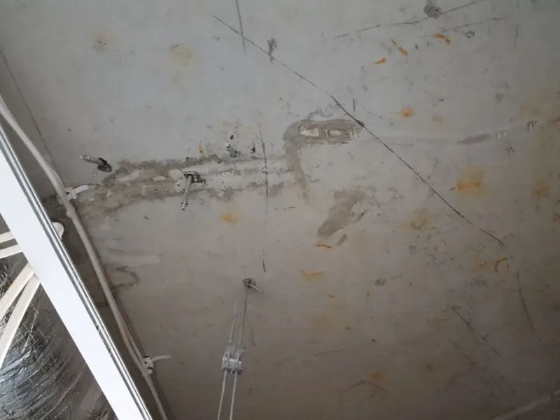 Sufit z rysą i pakerami przy oknie, widoczne przewody instalacji
