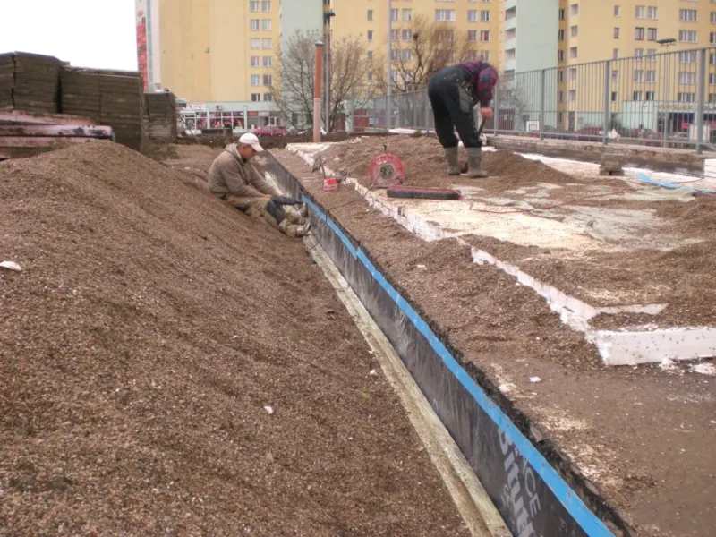 Pracownicy przy zasypywaniu wykopu wzdłuż izolacji fundamentów