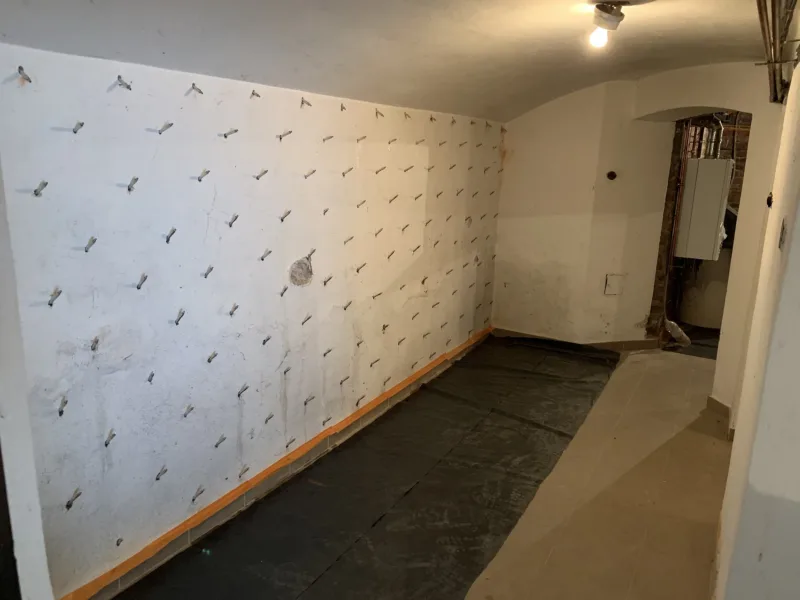 Ściana sklepionej piwnicy z rzędami pakerów iniekcyjnych, posadzka zabezpieczona folią