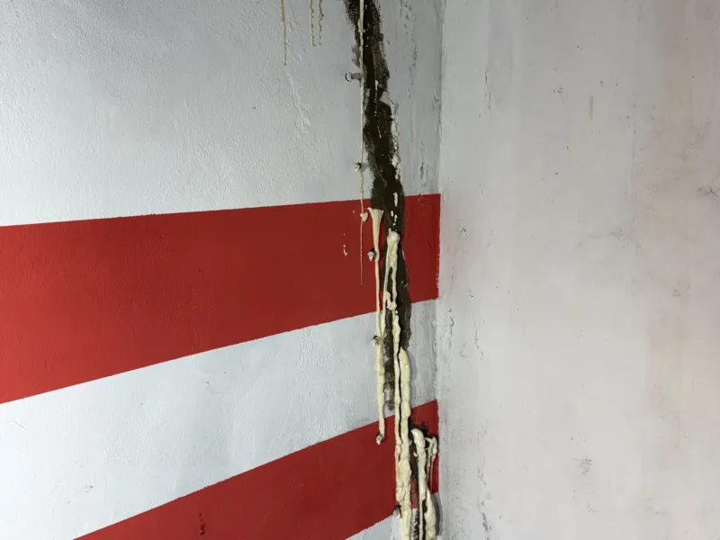 Pionowa rysa w ścianie garażu wypełniona preparatem po iniekcji