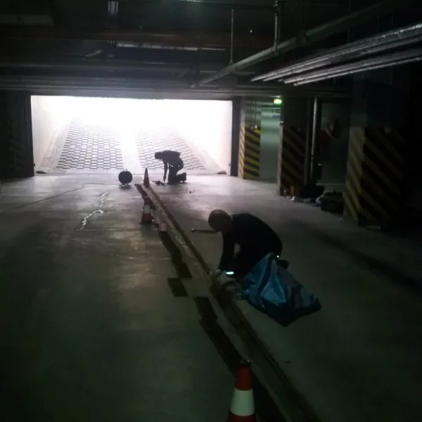 Pracownicy przy dylatacji w posadzce garażu, w tle wjazd