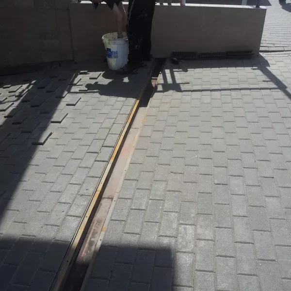 Pracownik przy uszczelnianiu szczeliny w nawierzchni z kostki
