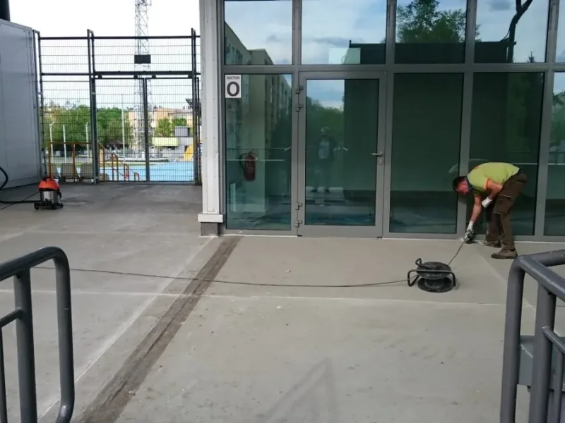 Pracownicy przy przygotowaniu nawierzchni tarasu przed przeszklonym wejściem