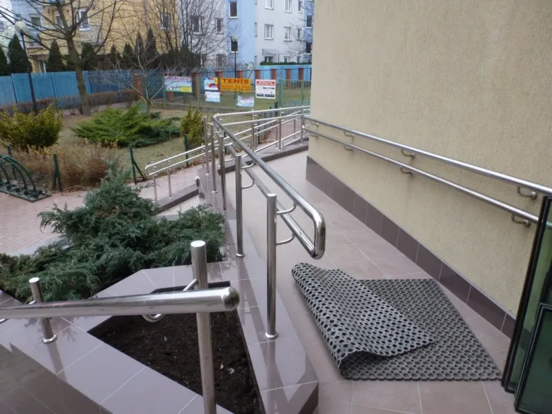 Taras przy wejściu z balustradami i donicą z roślinami