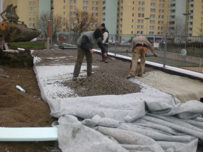 Rozkładanie żwiru na geowłókninie na stropie przy osiedlu