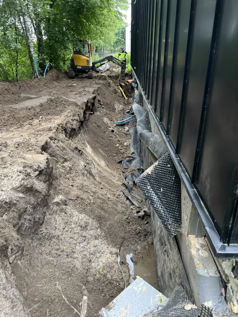 Wykop przy ścianie fundamentowej z izolacją i folią kubełkową